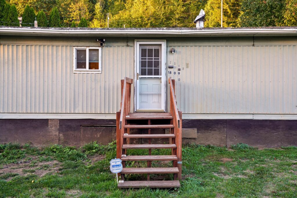 The exterior of one of a metal home with a short staircase to the door, a whitish exterior, and one window before one of SWF's manufactured home inspections